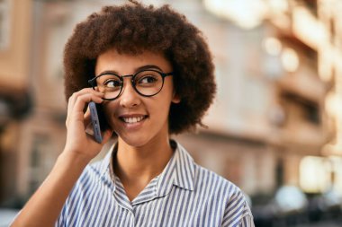 Genç İspanyol iş kadını gülümsüyor. Şehirdeki akıllı telefondan mutlu bir şekilde konuşuyor..