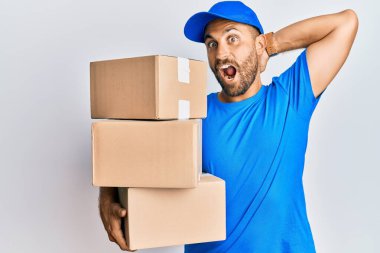 Sakallı, kurye üniforması giyen yakışıklı bir adam teslimat paketlerini taşırken çıldırmış ve elleri başının üstünde korkmuş, ağzı açık bir şekilde şok geçirmekten korkan ve şaşırmış. 