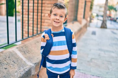 Sevimli beyaz bir öğrenci şehirde mutlu bir şekilde gülümsüyor..