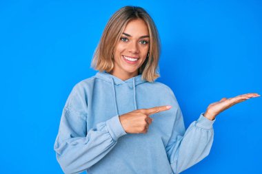 Güzel, beyaz bir kadın, sıradan bir kazak giyip kameraya hayret ediyor ve gülümsüyor.. 