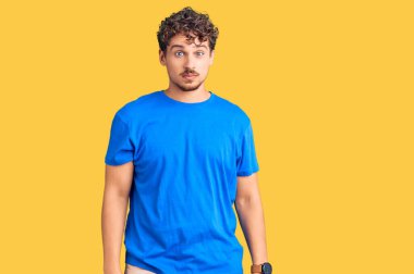 Kıvırcık saçlı, sıradan giyinen, kuşkucu ve gergin, sorunlarından dolayı üzgün olan genç yakışıklı bir adam. negatif kişi. 