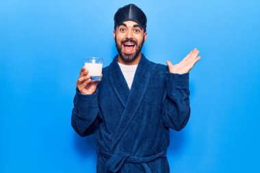Genç İspanyol adam uyku maskesi takmış ve bornoz giyiyor. Süt içiyor, başarıyı kutluyor. Mutlu bir gülümsemeyle ve kazanan yüz ifadesiyle elini kaldırarak. 