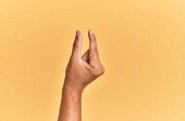 Beyaz adamın kolu ve eli sarı izole edilmiş arka plan üzerinde ve görünmez şeyi alıyor, parmakları boşluk gösteren nesneyi tutuyor. 