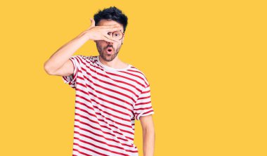 Gündelik kıyafetler giyen genç İspanyol adam şok içinde yüzünü ve gözlerini kapayarak utanmış ifadesiyle parmaklarından bakıyor.. 