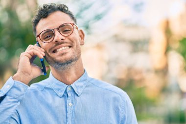 Genç İspanyol işadamı gülümsüyor. Şehirdeki akıllı telefondan mutlu bir şekilde konuşuyor..