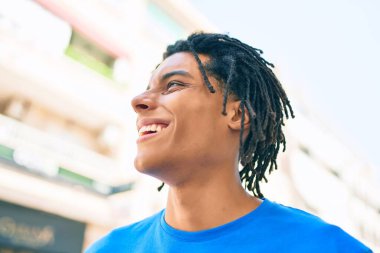 Genç Afrikalı Amerikalı gülümseyen mutlu bir adam şehrin caddesine bakıyor..