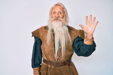 Gri saçlı, uzun sakallı, Viking kostümü giyen yaşlı bir adam. Beş numarayı gösterip gülümserken kendinden emin ve mutlu bir şekilde işaret ediyor.. 
