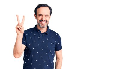 Orta yaşlı yakışıklı, sıradan polo giyen, gülümseyen, kameraya göz kırpan ve zafer işareti yapan bir adam. İki numara.. 