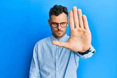 Günlük kıyafetler giyen ve gözlük takan İspanyol genç adam avucunun içi gibi şarkı söylemeyi kesiyor. Yüzünde olumsuz ve ciddi bir jest olan uyarı ifadesi. 