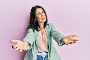 Orta yaşlı esmer kadın gündelik kıyafetler giyiyor. Gülümsüyor, yardım eli uzatıyor ve kabul ediyor.. 