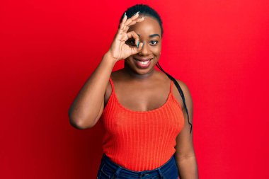 Genç Afro-Amerikalı kadın yüzünde mutlu ve havalı bir gülümseme ile gözünün üstüne imza atıyor. diş gösterme. 