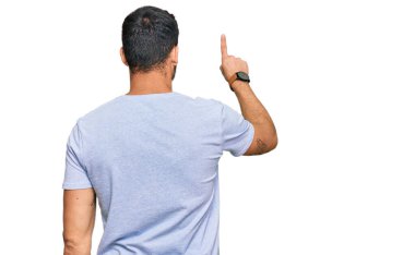 Latin asıllı genç adam gündelik giysiler giyip geriye doğru poz veriyor. 