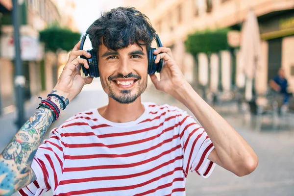 Νεαρός Ισπανόφωνος Χαμογελώντας Χαρούμενος Και Χρησιμοποιώντας Ακουστικά Περπατώντας Στο Δρόμο — Φωτογραφία Αρχείου