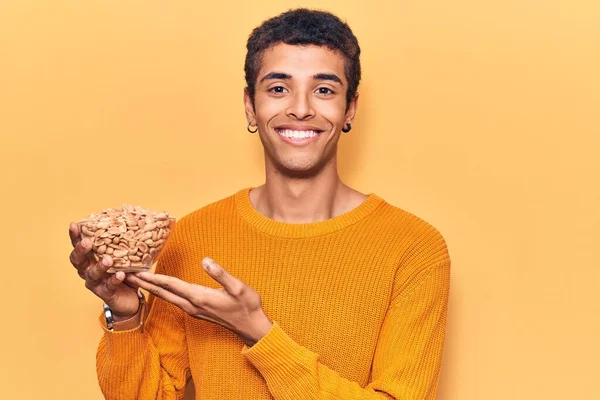 Fıstık tutan Afrikalı genç bir Amerikalı. Olumlu ve mutlu görünüyor. Kendine güvenen bir gülümsemeyle dişlerini gösteriyor. 