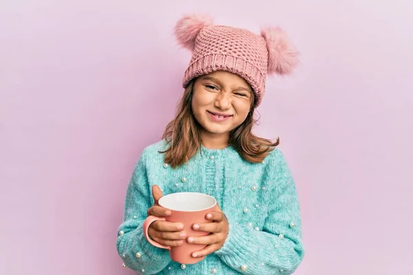 Kleines Hübsches Mädchen Mit Rosa Becher Mit Süßer Wollmütze Zwinkert — Stockfoto