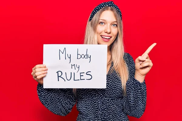 Young Blonde Woman Holding Body Rules Banner Smiling Happy Pointing — Stock Photo, Image