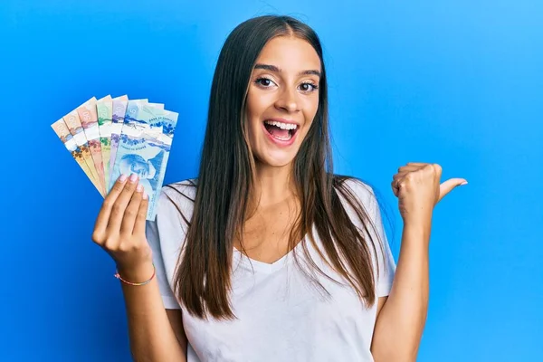 Joven Mujer Hispana Sosteniendo Dólares Canadienses Apuntando Con Pulgar Hacia — Foto de Stock