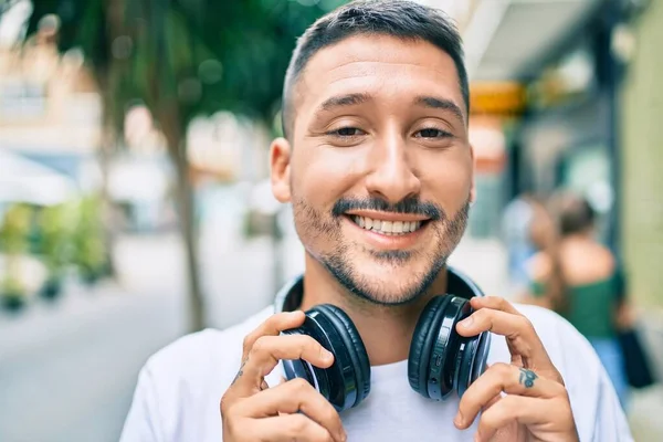 Młody Latynos Uśmiechnięty Szczęśliwy Słuchając Muzyki Pomocą Słuchawek Ulicy Miasta — Zdjęcie stockowe