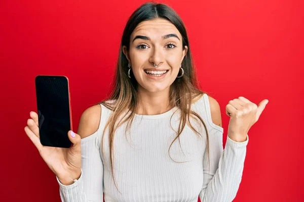 Young Hispanic Woman Holding Smartphone Showing Blank Screen Pointing Thumb — Stock Photo, Image