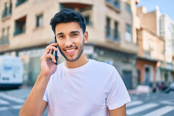 若いラテン語の男笑顔幸せな話上のスマートフォンで街を歩く — ストック写真