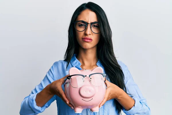 Beautiful Hispanic Woman Holding Piggy Bank Glasses Clueless Confused Expression — Stock Photo, Image