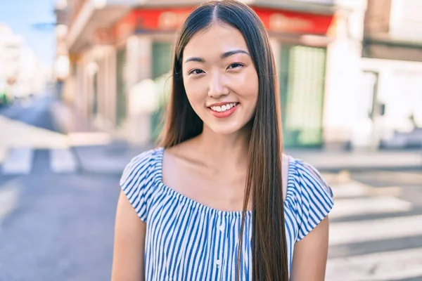 Genç Çinli kadın gülümsüyor. Şehrin caddesinde mutlu bir şekilde yürüyor..