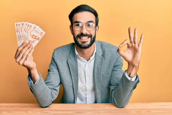Genç İspanyol adam elinde Türk lirası banknotları tutuyor. Tamam işareti yapıyor, gülümsüyor. Mükemmel bir sembol. 