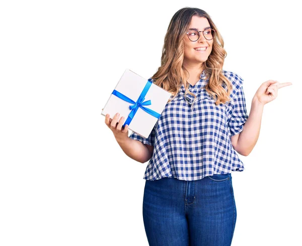 Joven Mujer Caucásica Sosteniendo Regalo Sonriendo Feliz Señalando Con Mano —  Fotos de Stock