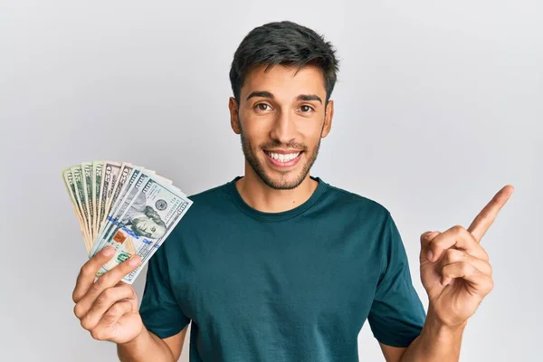 Joven Hombre Guapo Sosteniendo Dólares Sonriendo Feliz Señalando Con Mano —  Fotos de Stock