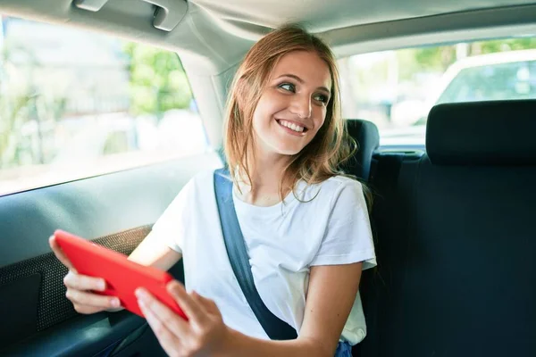 Genç Güzel Sarışın Gülümseyen Bir Kadın Tablet Kullanarak Arabada Oturuyor — Stok fotoğraf