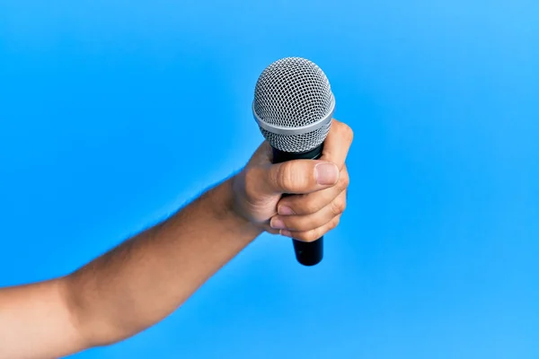 Mano Del Hombre Hispano Sosteniendo Micrófono Sobre Fondo Azul Aislado — Foto de Stock