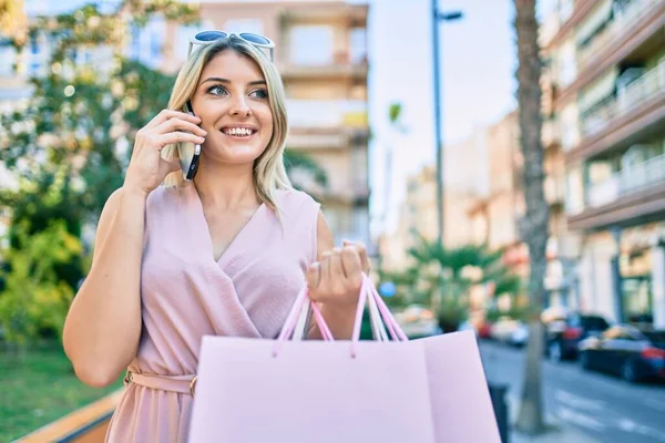 Genç sarışın kadın gülümsüyor. Akıllı telefondan konuşmaktan mutlu oluyor. Şehre alışverişe gidiyor..