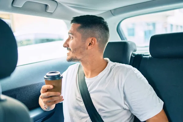若いですヒスパニック系の男笑顔幸せな飲み物取りますコーヒー座って車の上に — ストック写真