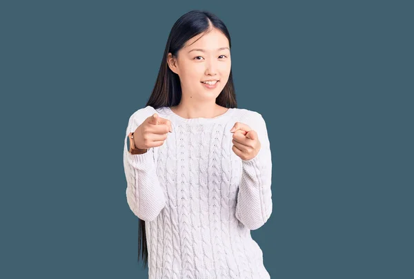 若い美しい中国の女性が幸せと面白い顔でカメラに指を指してカジュアルなセーターを着ています 良いエネルギーと振動は — ストック写真
