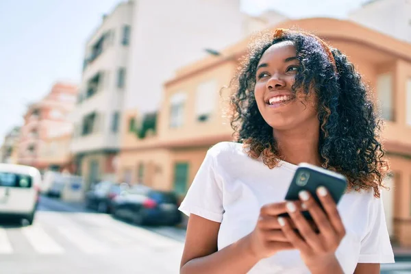 若いですアフリカ系アメリカ人女性とともに巻き毛笑顔幸せな屋外で使用スマートフォン — ストック写真