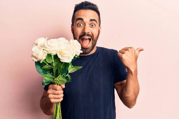 Jovem Hispânico Segurando Flores Apontando Polegar Para Lado Sorrindo Feliz — Fotografia de Stock