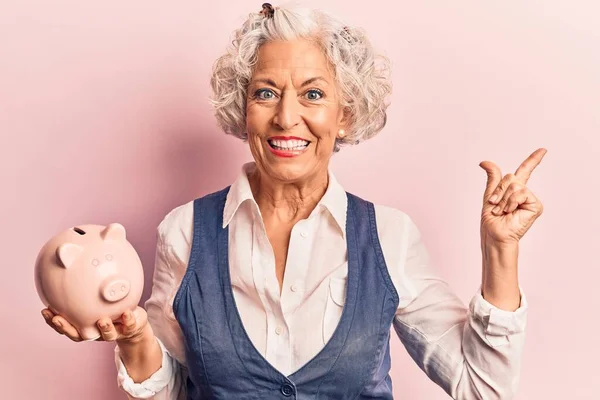 Senior Gråhårig Kvinna Håller Spargris Bank Ler Glad Pekar Med — Stockfoto
