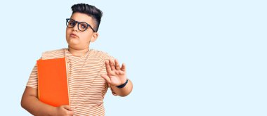 Küçük çocuk kitap tutuyor, gözlük takıyor. Avuçlarıyla jestler yapıyor. Öfkeli ve hayal kırıklığı dolu bir ifade. 