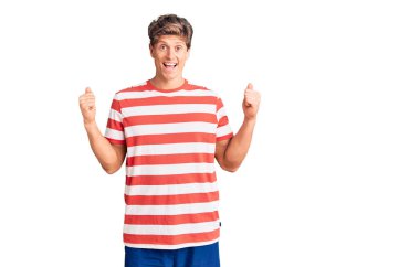 Gündelik giysiler giyen genç yakışıklı adam şaşkınlık ve şaşkınlık içinde kollarını kaldırarak ve gözlerini açarak başarıyı kutluyor. Kazanan konsept. 