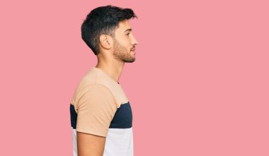 Sıradan kıyafetler giyen, rahat bir görünüm takınan, doğal yüzlü ve kendine güvenen genç yakışıklı bir adam.. 