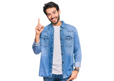 Gündelik kıyafetler giyen genç İspanyol bir numarayı gösterip işaret ederken kendinden emin ve mutlu bir şekilde gülümsüyor.. 