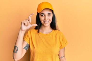 Dağıtım üniforması giyen, şapkalı, gülümseyen, kendine güvenen, el hareketi yapan, parmaklarıyla işaret eden ve kameraya bakan İspanyol bir kadın. ölçüm kavramı. 