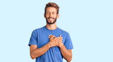 Sarışın, sakallı, sıradan kıyafetler giyen, göğsünde elleri kapalı, yüzünde minnet ifadesi olan yakışıklı bir adam. sağlık kavramı. 