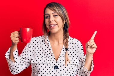 Genç ve güzel bir kadın kahve fincanı içerken gülümsüyor. 