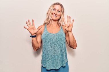 Orta yaşlı beyaz kadın spor giysisi giyer ve dokuz numaralı parmaklarını göstererek gülümserken kendinden emin ve mutlu.. 