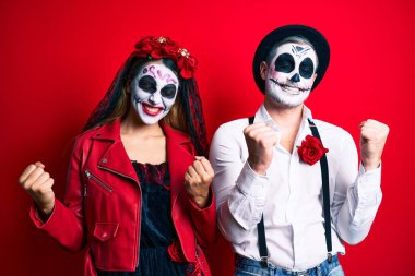 Ölü kostümün giyildiği gün mutlu ve heyecanlı bir şekilde kolları havada, gülümseyen ve başarı çığlıkları atan bir çift. kutlama konsepti. 