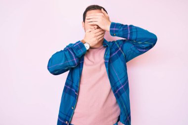 Gündelik kıyafetler giyen genç yakışıklı adam gözlerini ve ağzını elleriyle kapatıyor, şaşırmış ve şok olmuş. duygu gizleme 