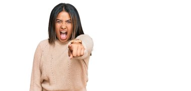 Kışın yün kazak giyen genç Latin kız kameraya kızgın ve sinirli bir şekilde seni işaret ediyor. 