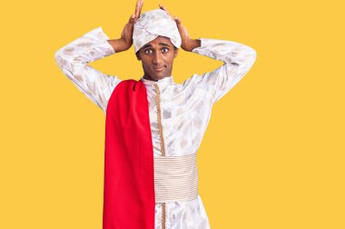 Gelenek giyinmiş Afrikalı yakışıklı bir adam Sherwani sari elbisesi giyiyor. Tavşan kulakları yapıyor. Avuçlarıyla alaycı ve şüpheci görünüyor. Paskalya tavşanı konsepti. 