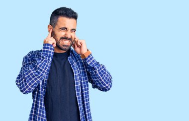 Gürültülü müzik sesi için günlük kıyafetler giyen genç İspanyol adam kulaklarını parmaklarıyla kapatıyor. sağır kavramı. 